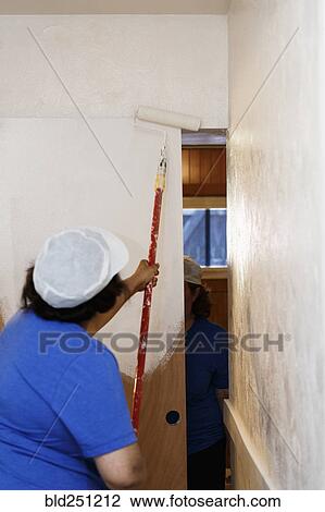 Stock Image - Native American woman painting wall. Fotosearch