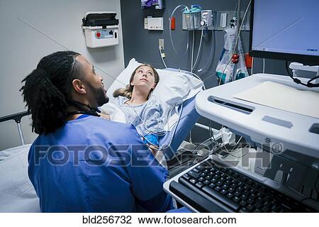 Stock Image - Nurse and patient looking at monitor in hospital. Fotosearch