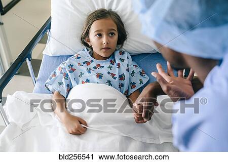 Stock Image - Nurse holding hands and talking to girl. Fotosearch