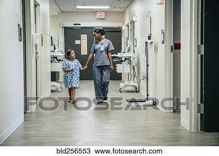 Stock Image - Nurse holding hands with girl in hospital. Fotosearch