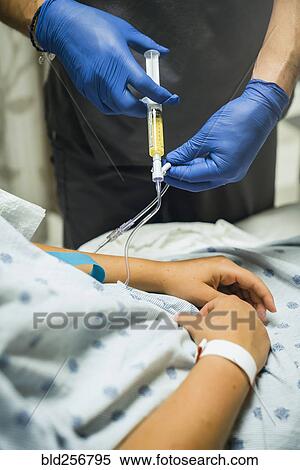 Stock Photography - Nurse injecting medicine into tube of patient. Fotosearch