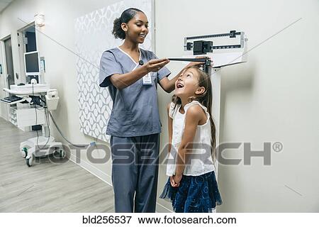 Stock Photo - Nurse measuring height of girl. Fotosearch
