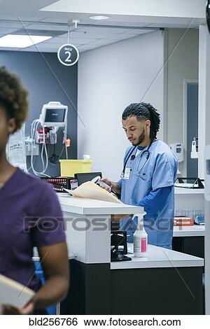 Nurse scanning paperwork in hospital View Large Photo Image Stock Photograph - Nurse scanning paperwork in hospital. Fotosearch