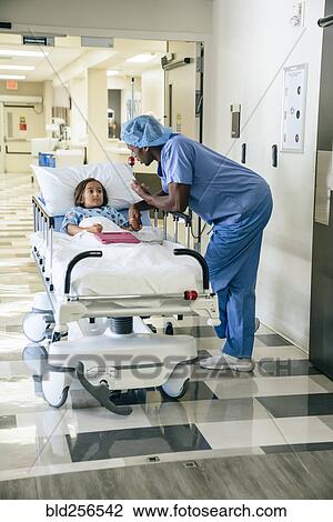 Stock Image - Nurse talking to girl in hospital gurney. Fotosearch