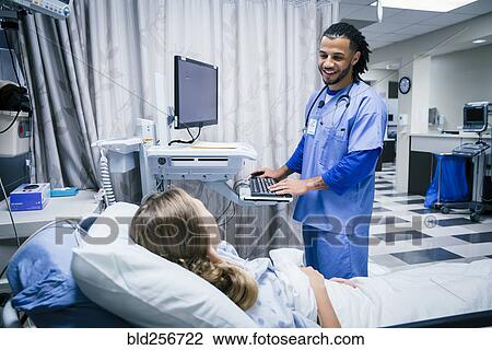 Stock Image - Nurse talking to patient in hospital bed. Fotosearch