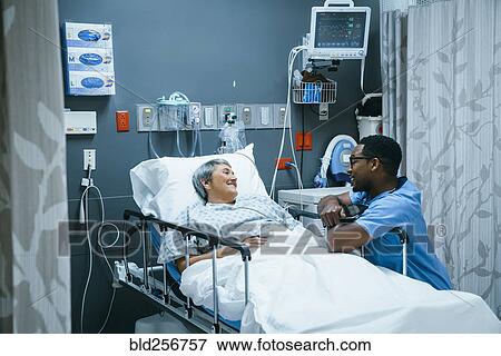 Stock Photo - Nurse talking to patient in hospital bed. Fotosearch