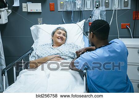 Stock Photo - Nurse talking to patient in hospital bed. Fotosearch