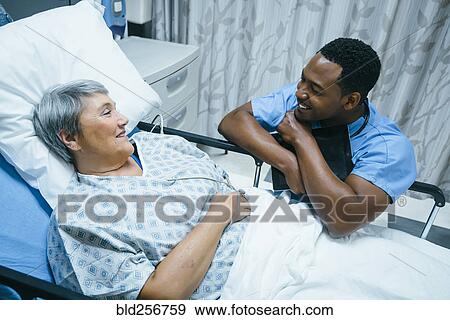 Stock Photo - Nurse talking to patient in hospital bed. Fotosearch