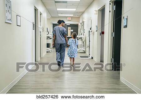 Stock Photograph - Nurse walking with girl in hospital corridor. Fotosearch