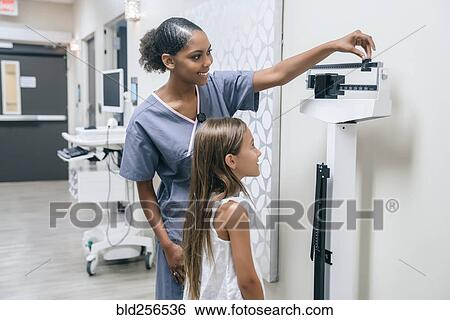 Stock Photograph - Nurse weighing girl on scale. Fotosearch