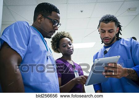 Stock Photograph - Nurses discussing digital tablet. Fotosearch