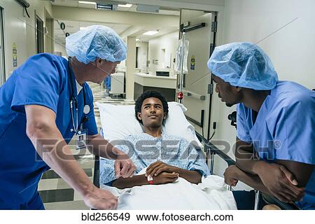 Stock Photo - Nurses talking to boy in hospital gurney. Fotosearch
