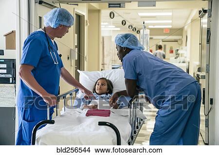 Picture - Nurses talking to girl in hospital gurney. Fotosearch