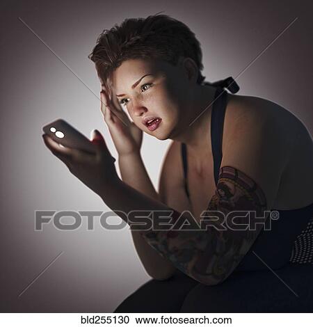 Stock Image - Overweight woman texting on cell phone. Fotosearch