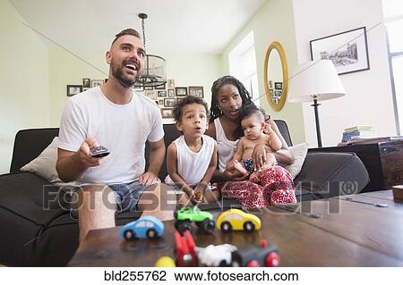 Stock Image - Parent watching television with son and daughter. Fotosearch