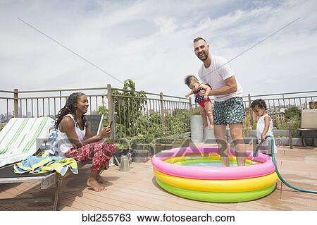 Parents playing with children in inflatable swimming pool View Large Photo Image Stock Image - Parents playing with children in inflatable swimming pool. Fotosearch