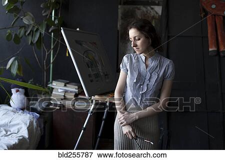 Stock Photo - Pensive Caucasian artist holding paintbrushes. Fotosearch