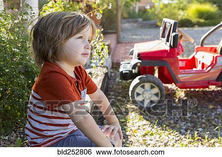 Pensive Caucasian boy sitting near toy car View Large Photo Image Stock Photograph - Pensive Caucasian boy sitting near toy car. Fotosearch