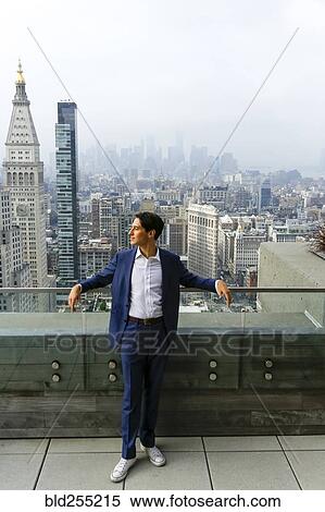 Stock Photography - Pensive Caucasian businessman leaning on urban rooftop. Fotosearch