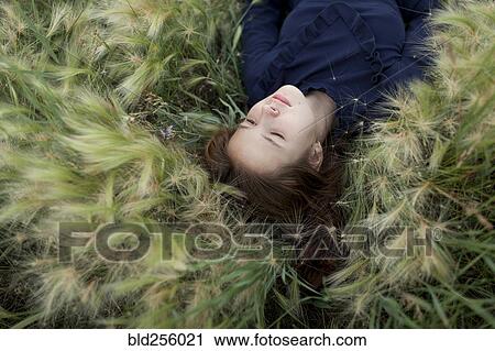 Pensive Caucasian girl laying in field View Large Photo Image Stock Image - Pensive Caucasian girl laying in field. Fotosearch