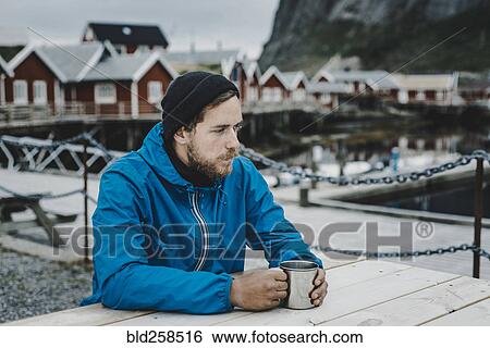 Pensive Caucasian man drinking coffee at table at waterfront View Large Photo Image Stock Photograph - Pensive Caucasian man drinking coffee at table at waterfront. Fotosearch