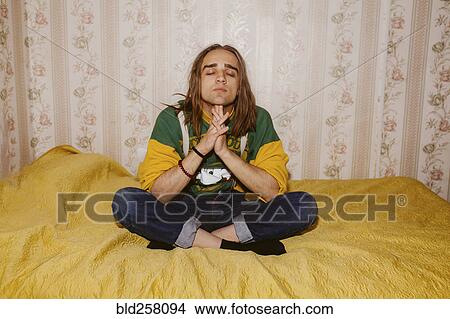 Pensive Caucasian man meditating on bed View Large Photo Image Picture - Pensive Caucasian man meditating on bed. Fotosearch