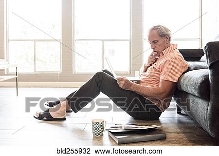 Pensive Caucasian man sitting on floor using laptop View Large Photo Image Stock Image - Pensive Caucasian man sitting on floor using laptop. Fotosearch