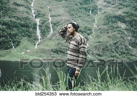 Stock Image - Pensive Caucasian man standing near river. Fotosearch