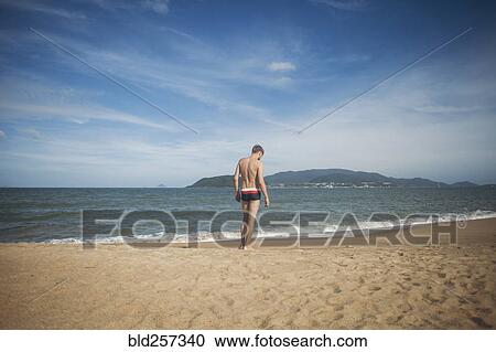 Stock Image - Pensive Caucasian man standing on beach. Fotosearch