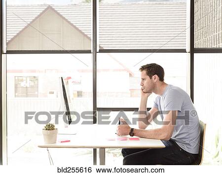 Stock Photograph - Pensive Caucasian man using computer. Fotosearch