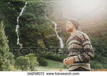 Stock Image - Pensive Caucasian man wearing sweater and hat outdoors. Fotosearch
