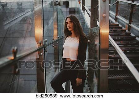 Stock Photo - Pensive Caucasian woman at window near staircase. Fotosearch