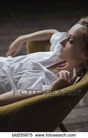 Stock Photography - Pensive Caucasian woman sitting in armchair. Fotosearch