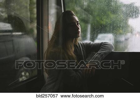 Stock Photo - Pensive Caucasian woman sitting on bus in rain. Fotosearch