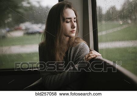 Stock Photo - Pensive Caucasian woman sitting on bus in rain. Fotosearch