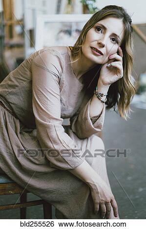 Stock Photograph - Pensive Caucasian woman sitting on chair. Fotosearch