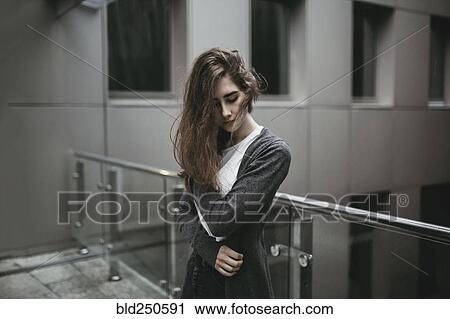 Stock Image - Pensive Caucasian woman standing near railing. Fotosearch