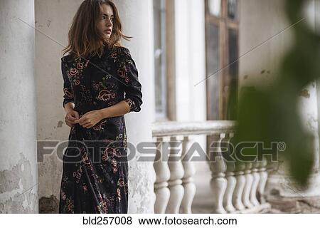 Stock Photo - Pensive Caucasian woman standing near pillar. Fotosearch