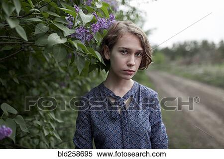 Stock Photography - Pensive Caucasian woman standing near flowers. Fotosearch