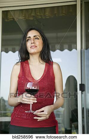 Stock Photograph - Pensive mixed race woman drinking wine. Fotosearch