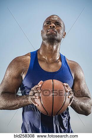 Stock Photo - Pensive sweating Black man holding basketball. Fotosearch