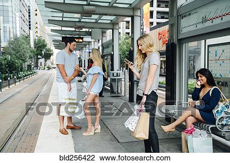 Stock Image - People at train station using cell phones. Fotosearch