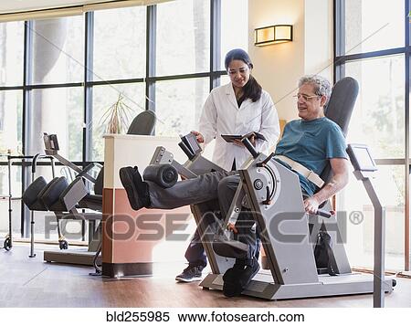Stock Photography - Physical therapist helping man strengthen legs. Fotosearch