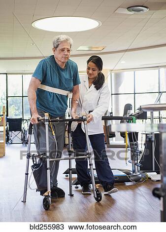 Stock Image - Physical therapist helping man using walker. Fotosearch