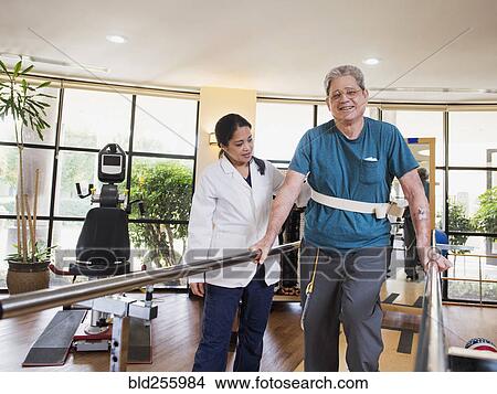 Picture - Physical therapist helping walking man. Fotosearch