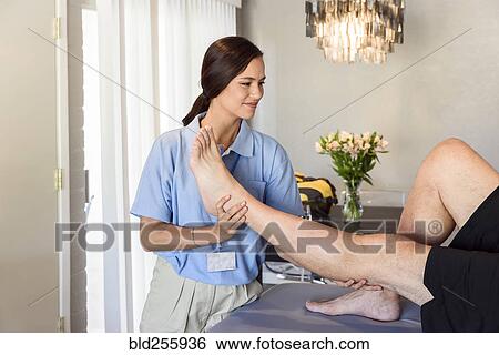Physical therapist lifting leg of man View Large Photo Image Stock Photograph - Physical therapist lifting leg of man. Fotosearch