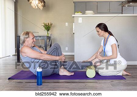 Stock Image - Physical therapist stretching leg of man. Fotosearch