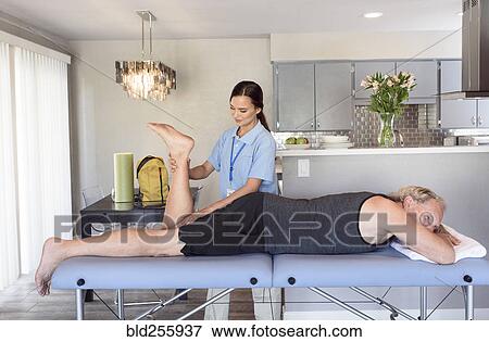 Stock Photo - Physical therapist stretching leg of man. Fotosearch