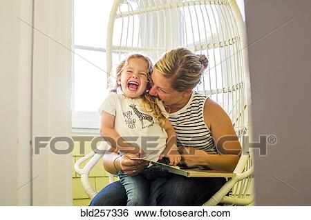 Playful Caucasian mother biting shoulder of daughter reading book View Large Photo Image Stock Photograph - Playful Caucasian mother biting shoulder of daughter reading book. Fotosearch