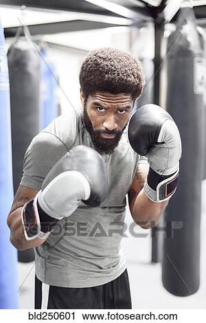 Stock Image - Portrait of Black man wearing boxing gloves in gymnasium. Fotosearch
